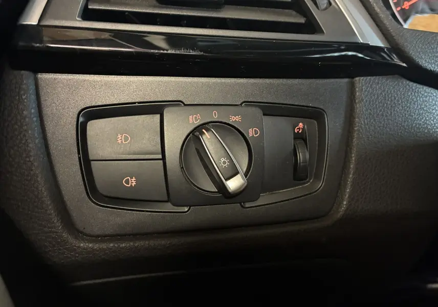 Gros plan sur le bouton de commande des phares du tableau de bord noir d'une BMW Série 4 Cabriolet F33 gris de 2019.