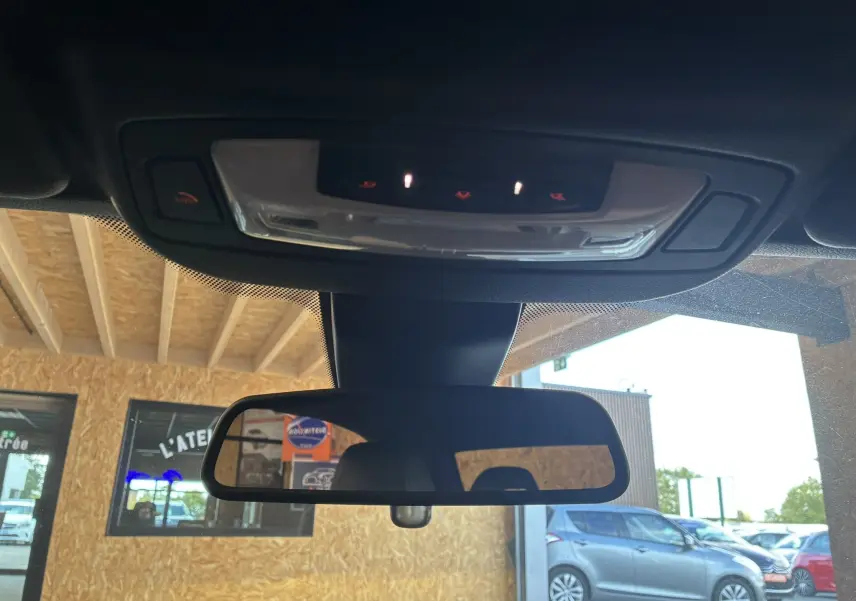 Vue intérieure du rétroviseur central et plafonnier de la BMW Série 4 Cabriolet gris, avec commandes éclairées au plafond.