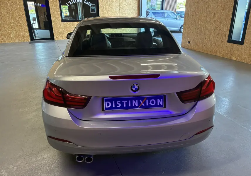 Vue arrière d'une BMW Série 4 Cabriolet gris métallisé 420i Luxury de 2019 avec double sortie d'échappement et plaque Distinxion.