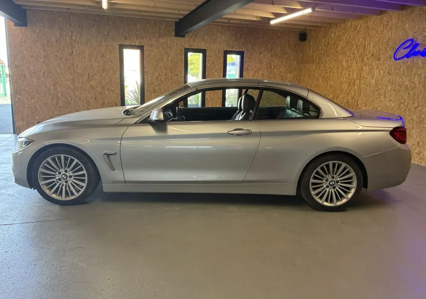 BMW Série 4 Cabriolet gris vue de profil côté gauche, toit rigide fermé, intérieur noir visible à travers les vitres.