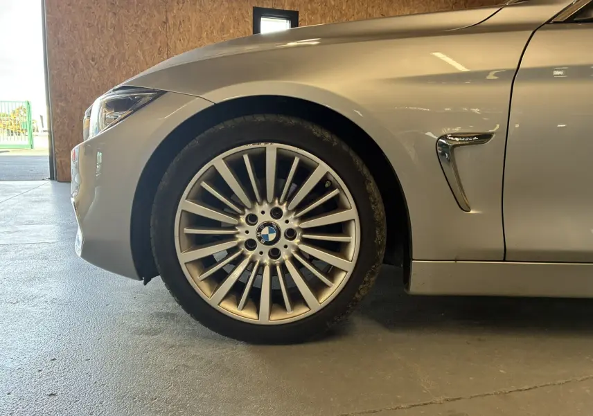 Gros plan sur la roue avant gauche et l'aile gris clair d'une BMW Série 4 Cabriolet F33 avec détail chromé sur l'aile.