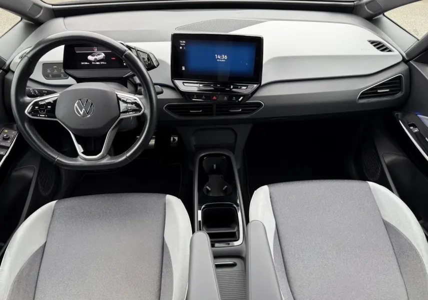 Intérieur avant du Volkswagen ID.3 2022 avec tableau de bord clair, volant cuir noir et écran tactile central.