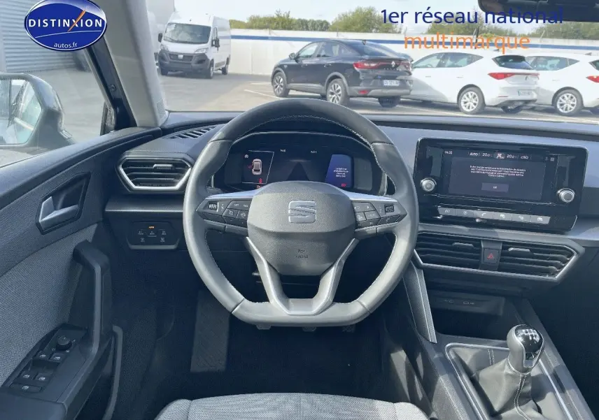 Vue intérieure centrée sur le volant et tableau de bord d'une SEAT Leon IV gris métallique avec boîte manuelle.