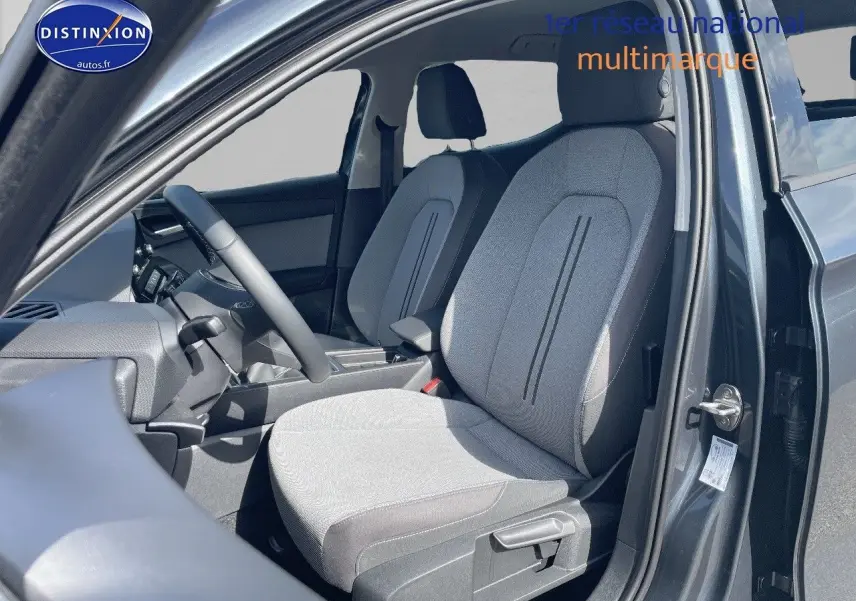 Vue intérieure côté conducteur du SEAT LEON gris magnétique métal, mettant en valeur les sièges en tissu gris clair et noir.