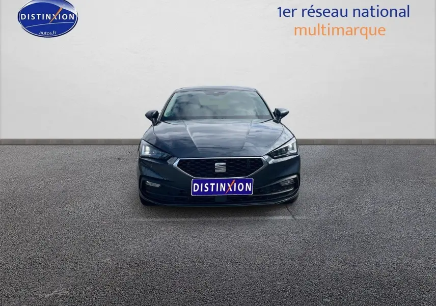 Vue frontale d'une SEAT LEON IV gris magnétique métal, avec calandre hexagonale et phares LED allumés.