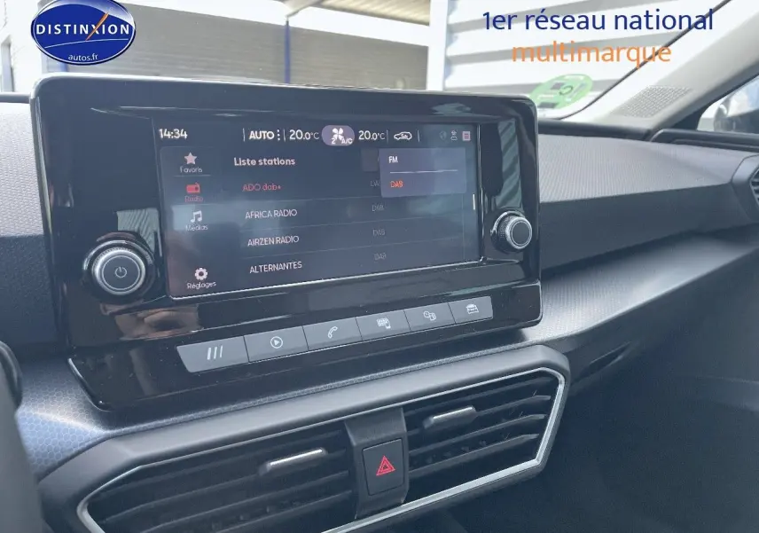 Vue intérieure du tableau de bord du SEAT Leon IV gris métallique, avec écran tactile central affichant les stations radio.