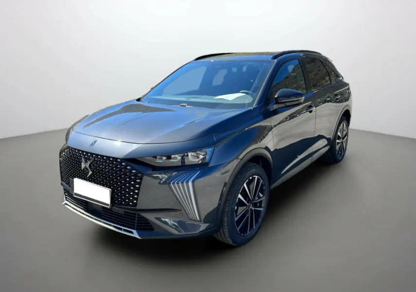 DS7 gris titane en 3/4 avant droit, avec calandre distinctive et jantes noires à motifs modernes.