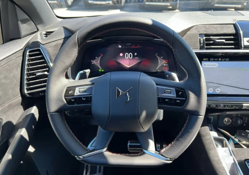 Vue centrée sur le volant du DS7 2025 gris titane, avec tableau de bord numérique et écran tactile de navigation.