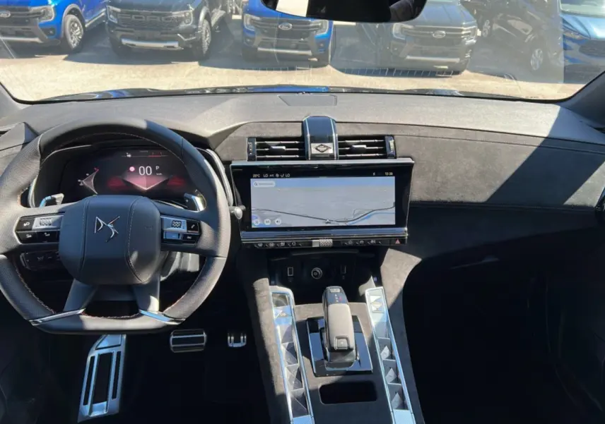 Vue intérieure avant du DS7 2025 gris titane, mettant en valeur le volant multifonction et l'écran tactile central large.