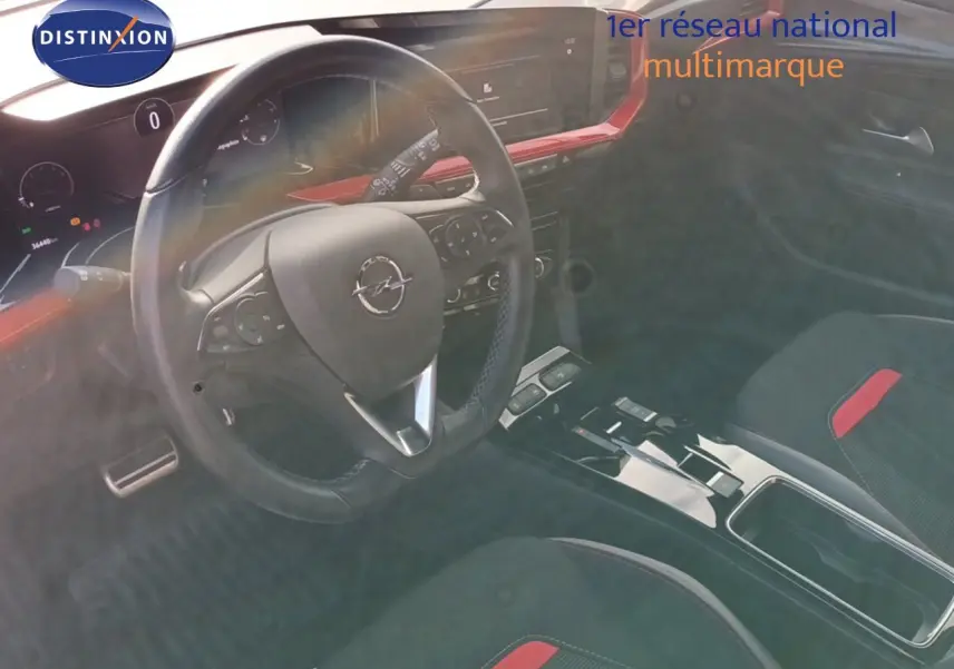 Intérieur de l'Opel Mokka GS Line 2022, vue du poste de conduite avec volant et console centrale noire et rouge.