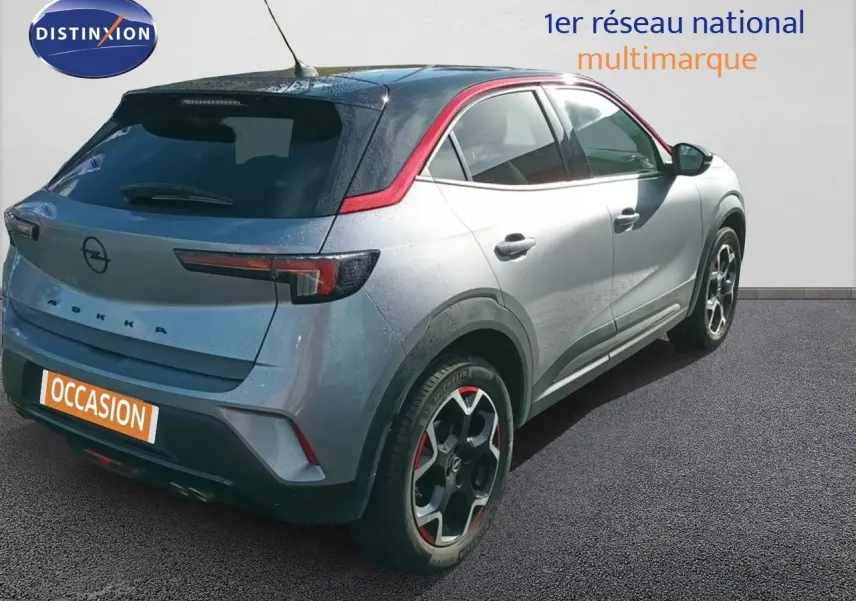 Vue 3/4 arrière droite de l'Opel Mokka GS Line 130ch BVA8 gris quartz avec toit noir et jantes bi-ton rouges.