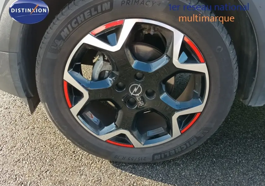 Gros plan sur la jante bi-ton noire et argent avec accents rouges d'un Opel Mokka GS Line gris quartz 2022.