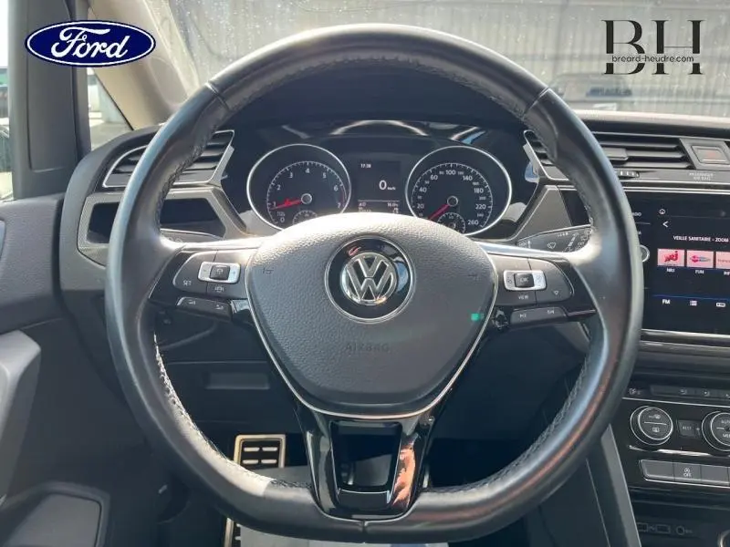 Vue intérieure centrée sur le volant cuir noir du Volkswagen Touran 2020 avec tableau de bord et écran tactile visibles.