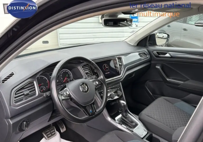 Vue intérieure côté conducteur du Volkswagen T-Roc noir 2020, avec tableau de bord moderne et volant multifonctions.