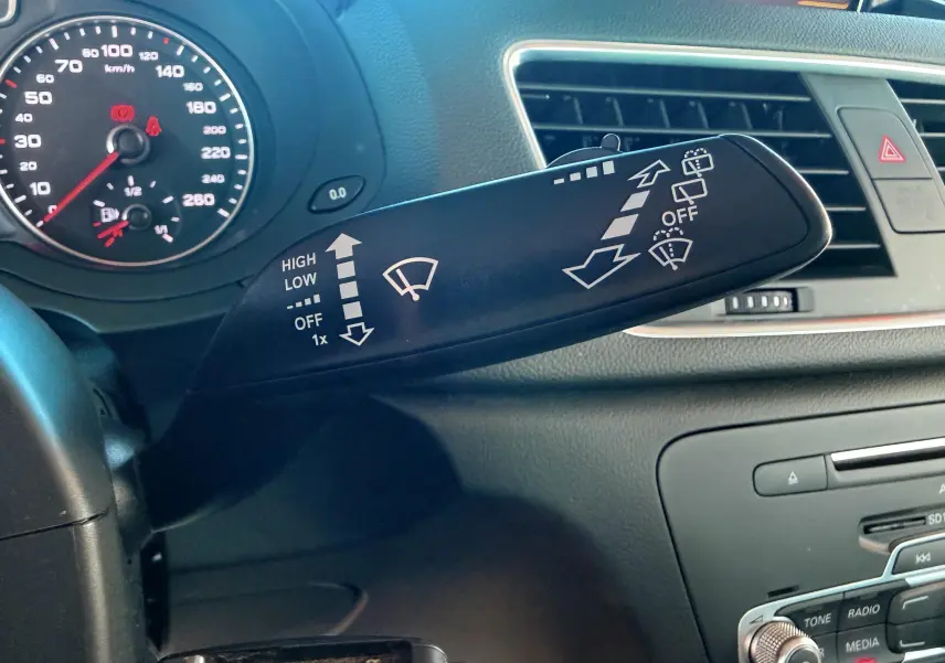 Gros plan sur la manette d’essuie-glace noire à gauche du volant dans l’habitacle noir de l’Audi Q3 2016.