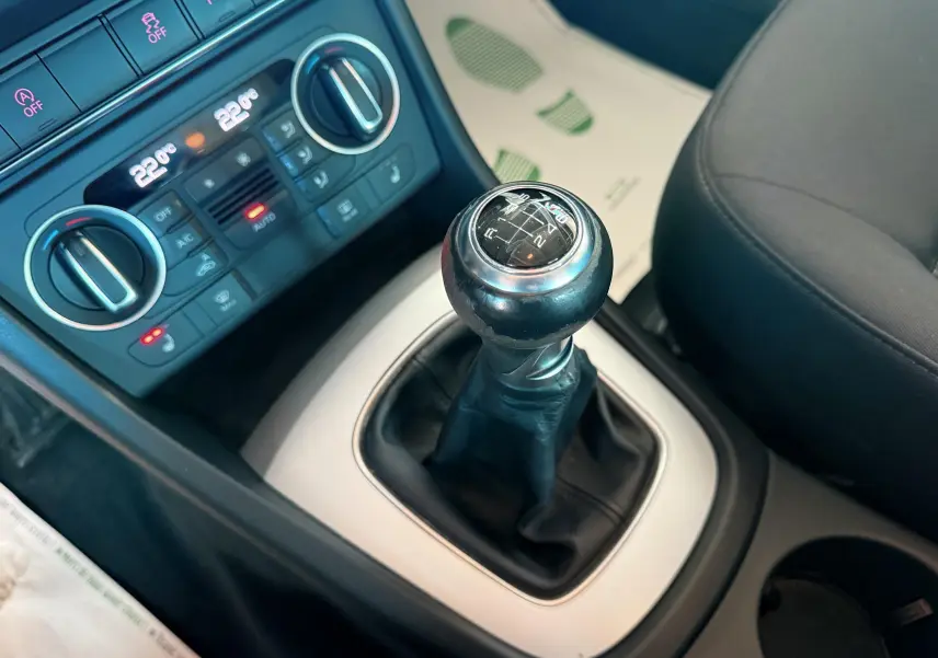 Gros plan sur le levier de vitesses manuel noir et la console centrale avec commandes de climatisation d’un Audi Q3 noir.