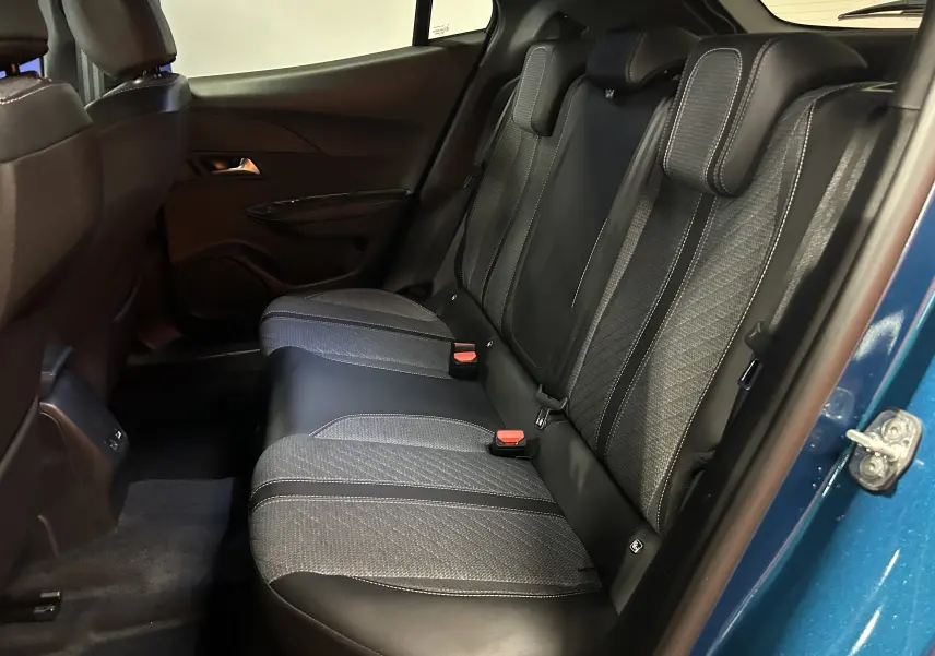 Vue intérieure arrière droite des sièges en tissu et cuir noir du Peugeot 2008 Bleu Obsession 2025, porte ouverte.