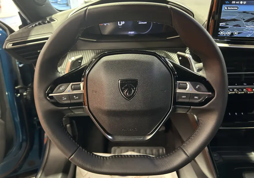 Vue rapprochée du volant cuir noir du Peugeot 2008 Bleu Obsession 2025 avec commandes intégrées et tableau de bord numérique.
