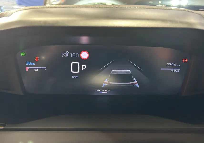 Affichage numérique du tableau de bord de la Peugeot 2008 bleu Obsession, montrant la vitesse et l'assistance à la conduite.