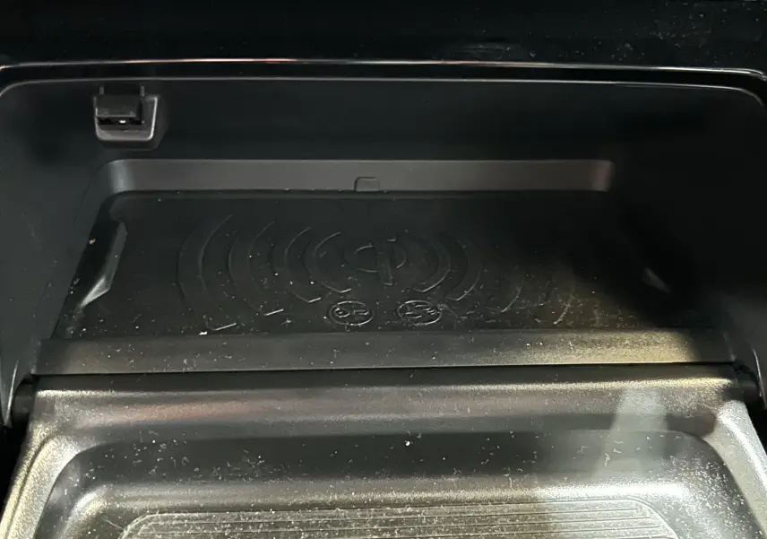 Gros plan sur le chargeur sans fil intégré dans le compartiment central du Peugeot 2008 Bleu Obsession 2025.