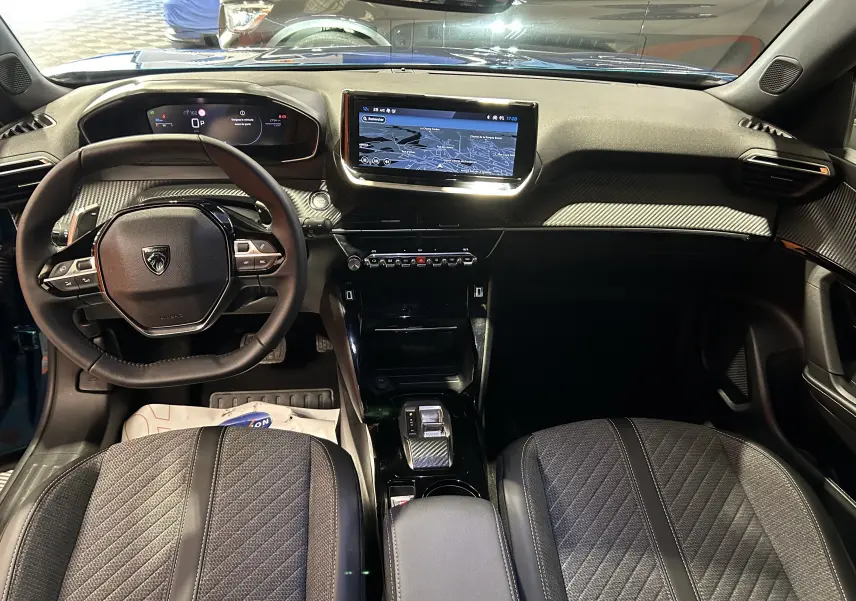 Vue intérieure avant du Peugeot 2008 II Ph.2 Allure Hybrid 145 en Bleu Obsession, avec tableau de bord numérique et écran tactile central.