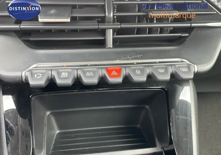 Vue rapprochée de la console centrale de la Peugeot 208 blanche, montrant les boutons de commande et les aérateurs.