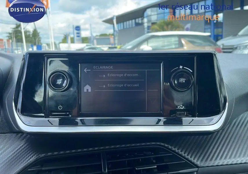 Écran tactile central du tableau de bord d'une Peugeot 208 blanche, avec commandes d'éclairage affichées.