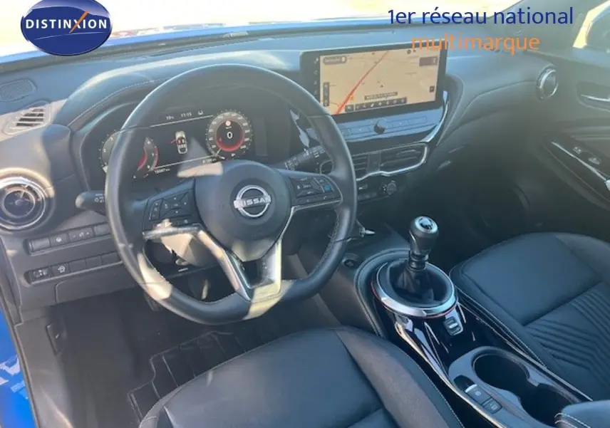 Vue intérieure du Nissan Juke 2025 bleu magnétique, montrant le volant, la boîte manuelle et l’écran tactile central.