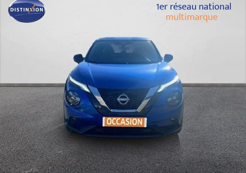 Vue frontale d'un Nissan Juke bleu magnétique métal avec calandre chromée et phares LED allumés.