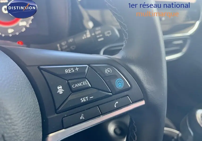 Gros plan sur les commandes au volant d’un Nissan Juke bleu magnétique, mettant en valeur les boutons de régulateur de vitesse.