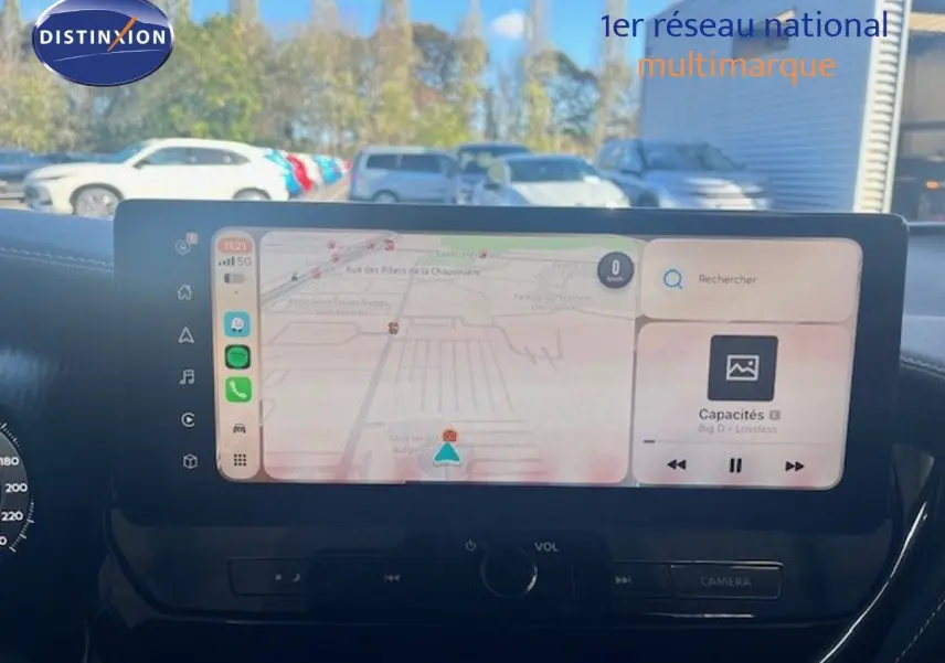 Vue intérieure du tableau de bord du Nissan Juke 2025 avec écran tactile affichant navigation et musique.