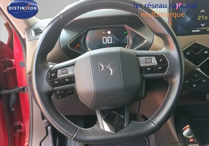 Vue intérieure centrée sur le volant cuir noir du DS3 Crossback rouge, avec tableau de bord numérique et écran tactile visible.