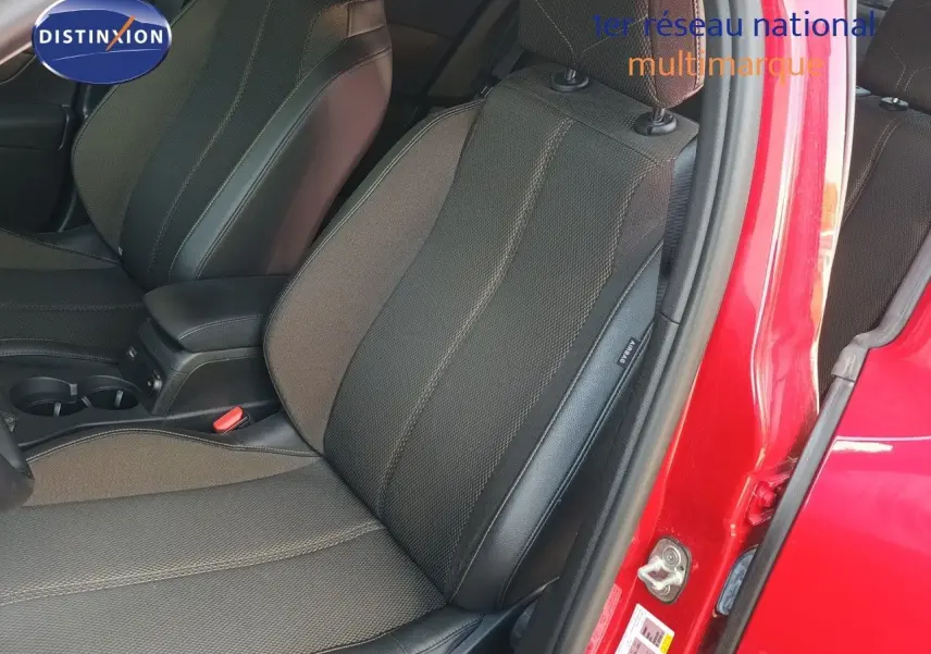 Vue intérieure côté conducteur du siège avant en tissu et cuir, portière ouverte sur carrosserie rouge métallisée.
