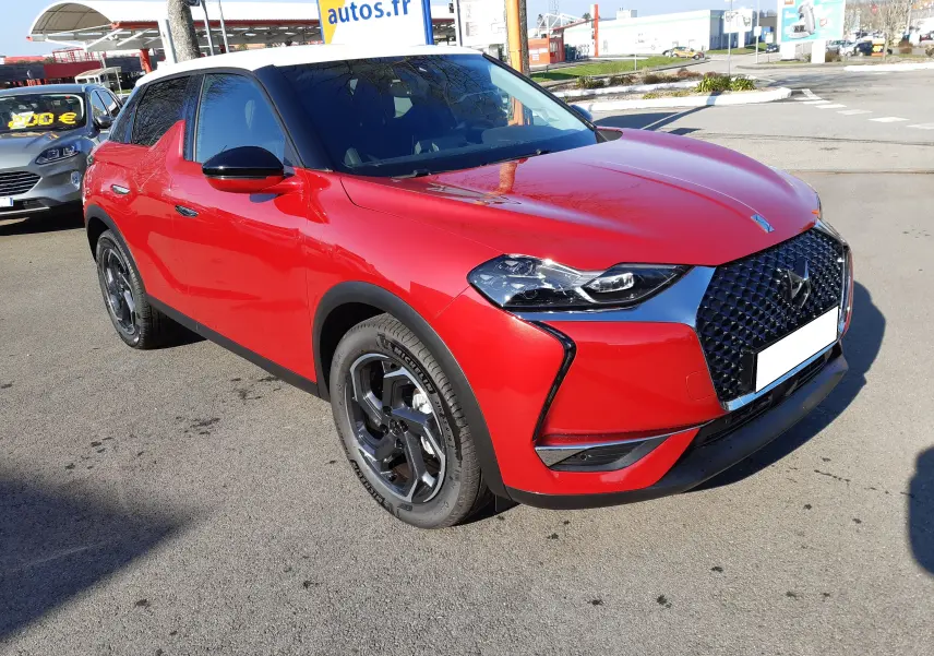 DS3 Crossback rouge métal avec toit blanc, vue 3/4 avant droit mettant en valeur la calandre distinctive et les jantes biton.