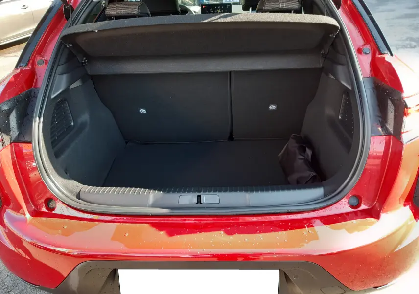 Coffre ouvert vu de l'arrière d'une DS3 Crossback rouge métal avec toit blanc, montrant l'espace de chargement vide.