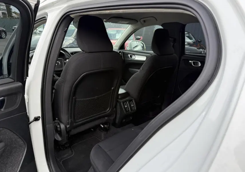 Intérieur arrière du Volvo XC40 blanc 2020, vue côté gauche avec sièges tissu noirs et console centrale visible.