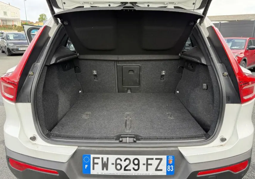 Coffre ouvert vu de l'arrière d'un Volvo XC40 blanc avec feux arrière rouges et plaque d'immatriculation française.