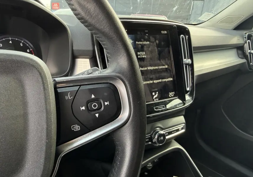 Vue intérieure du tableau de bord et volant cuir du Volvo XC40 Momentum 2020 essence, avec écran tactile central allumé.