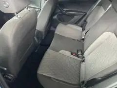 Vue latérale des sièges arrière en tissu gris clair du Volkswagen T-Cross 2024 bleu Sky Metal, intérieur spacieux et sobre.