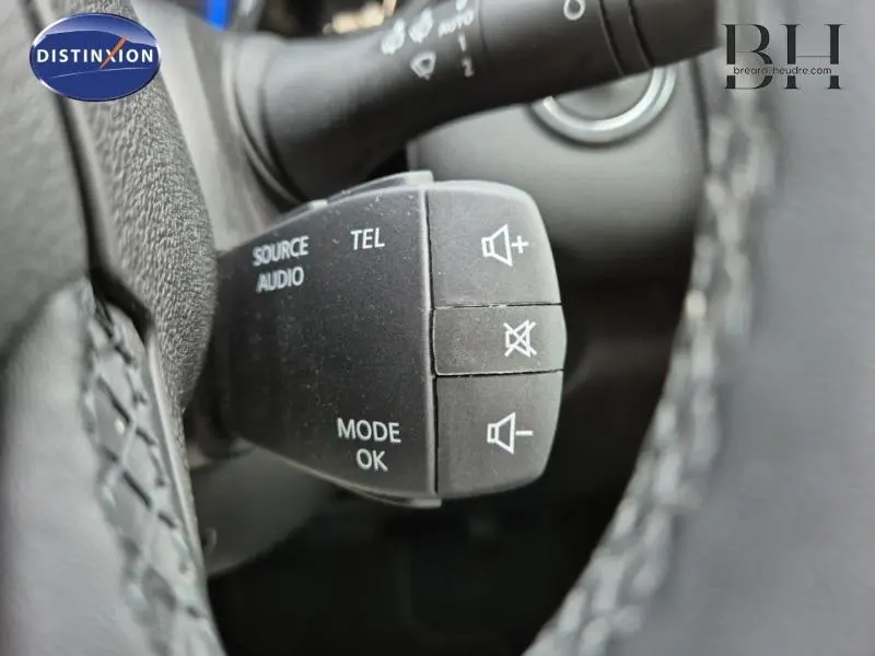 Gros plan sur les commandes audio au volant du Renault Kadjar blanc, avec boutons de volume et mode.