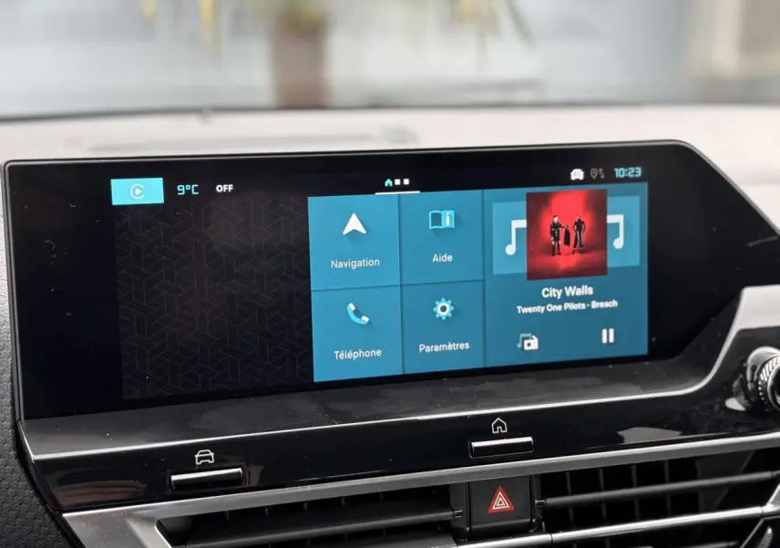 Écran tactile 10 pouces du tableau de bord Citroën C4 2024, affichant navigation et musique, ambiance intérieure noire.