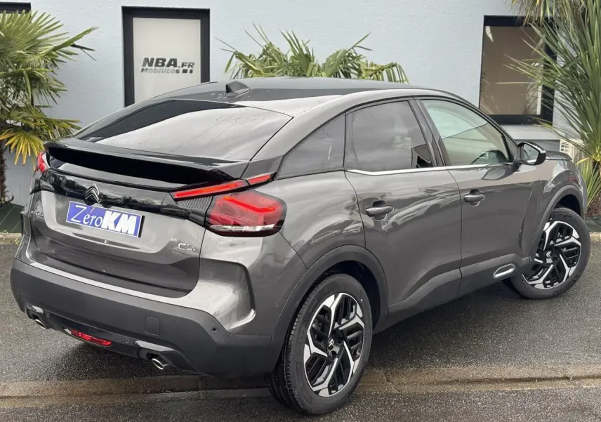 Vue 3/4 arrière droite d'une Citroën C4 2024 gris Platinium avec jantes alliage et feux arrière LED distinctifs.
