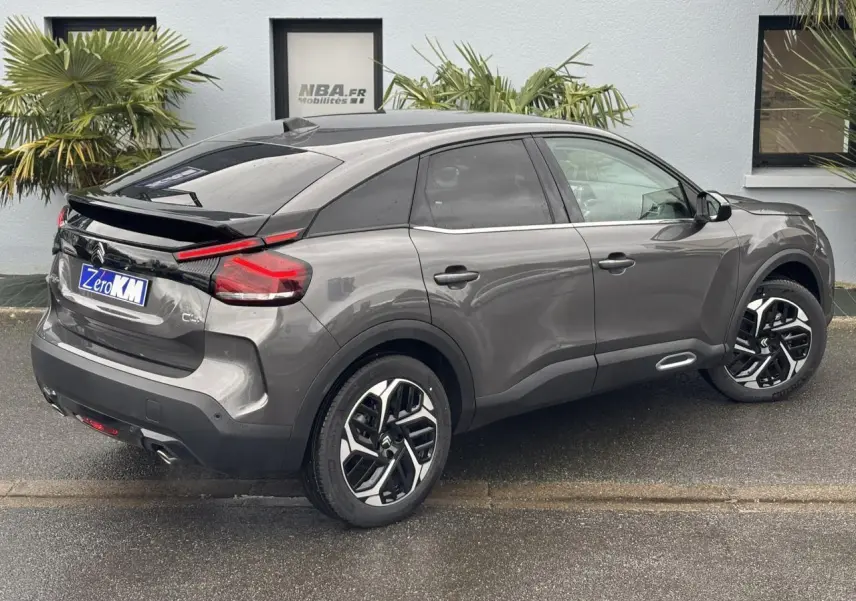 Vue 3/4 arrière droit d'une Citroën C4 2024 gris Platinium avec jantes alliage 18'' et vitres surteintées.