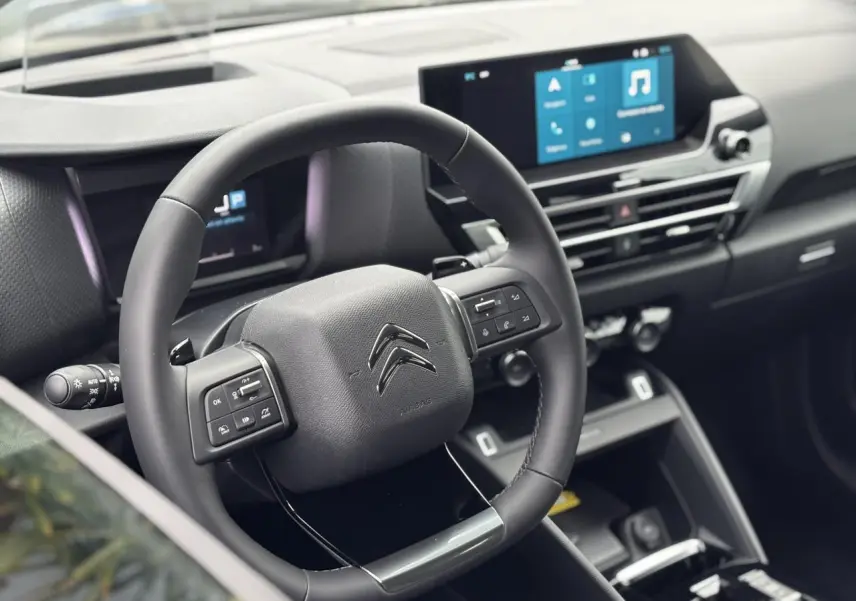 Vue intérieure centrée sur le volant cuir noir de la Citroën C4 2024 avec écran tactile et commandes au volant.