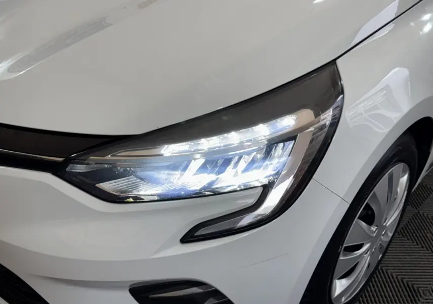 Gros plan sur l'avant droit blanc de la Renault Clio 2020 avec phares LED allumés et jante visible.