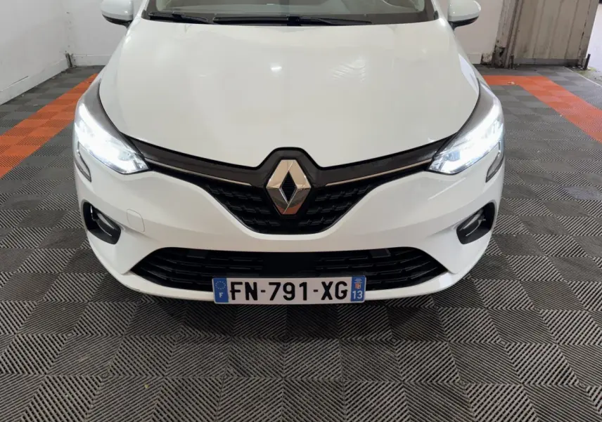 Vue avant d'une Renault Clio Business TCe 100 blanche avec phares LED allumés et calandre noire brillante.