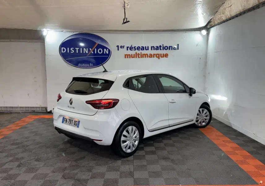 Renault Clio Business TCe 100 blanche vue 3/4 arrière droit dans un showroom avec logo Distinxion en arrière-plan.