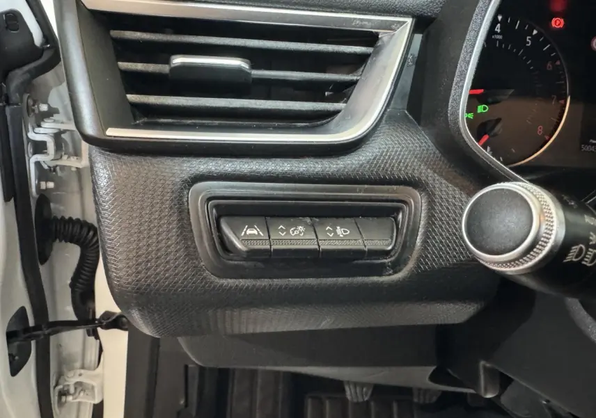 Gros plan sur les commandes d’assistance et réglage des phares du tableau de bord côté gauche d’une Renault Clio Business blanche 2020.