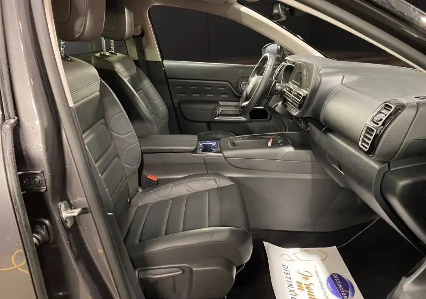 Vue intérieure côté conducteur du Citroën C5 Aircross 2023 gris platinium, sièges noirs en cuir et tableau de bord moderne.