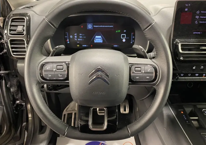 Vue rapprochée du volant cuir noir et du tableau de bord numérique du Citroën C5 Aircross 2023 gris platinium.